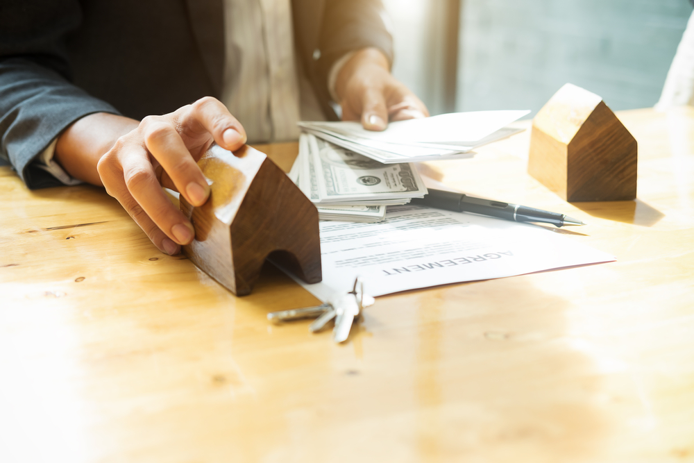 Man is handing money to real estate agent gives house keys to his client after signing contract